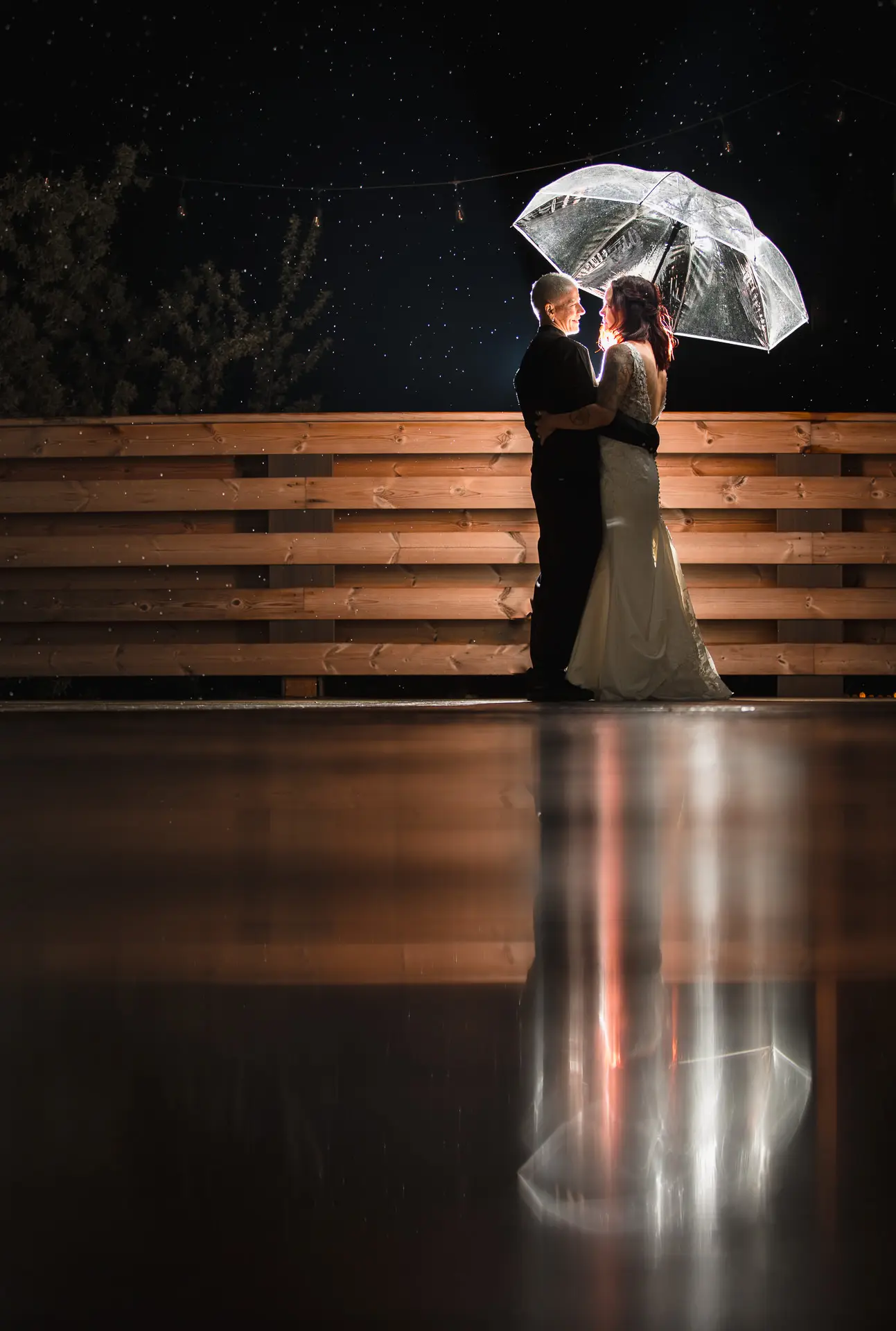 Two Colorado brides hugging in the rain withe an umbrella.