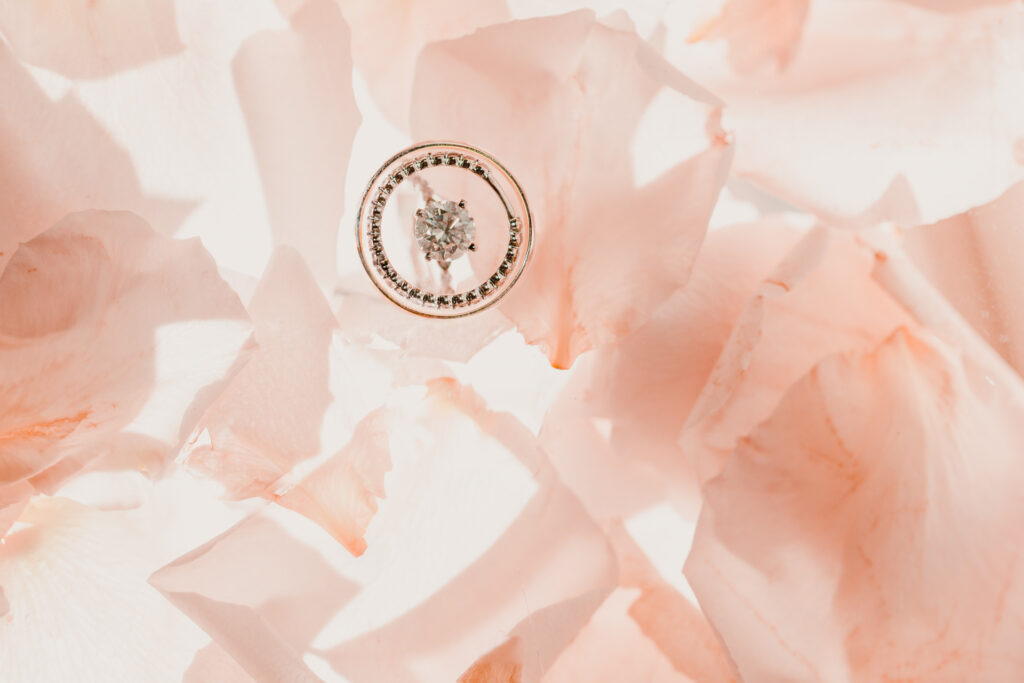 A minimalist photo of wedding rings with pink flower petals.