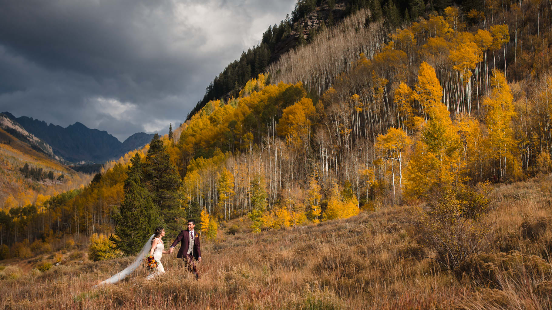 A Colorado bride and groom walk through the golden fall mountains in Vail, CO.